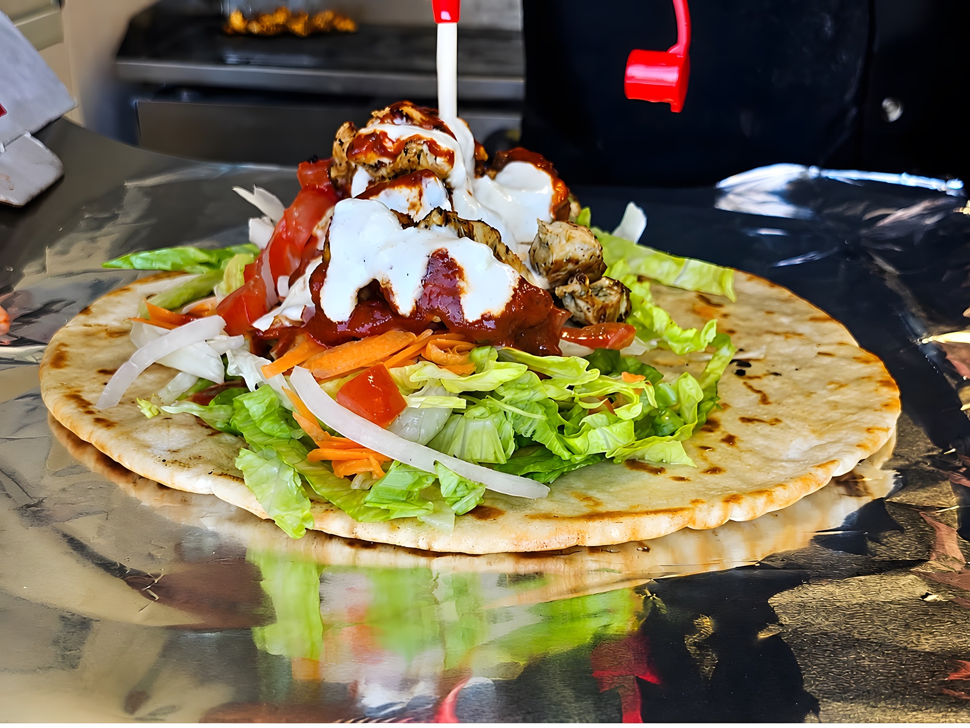 Open pita loaded with grilled meat, salad and sauces